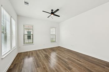A room with a ceiling fan and two windows at The Hadley - North Port, FL Apartments, North Port